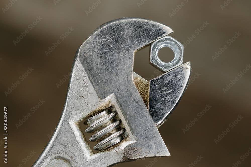 Old adjustable spanner or wrench gripping a hexagonal nut. Old adjustable spanner or wrench gripping a hexagonal nut.