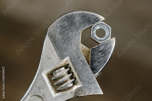 Old adjustable spanner or wrench gripping a hexagonal nut.