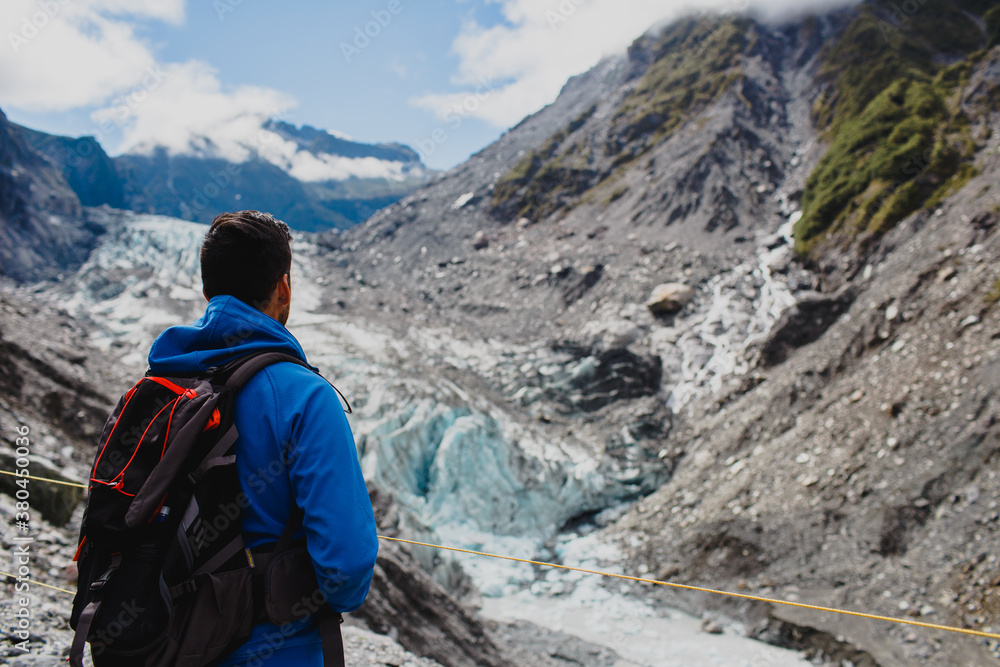 Young man from behind contemplating a glacier coming down from the mountain Young man from behind contemplating a glacier coming down from the mountain