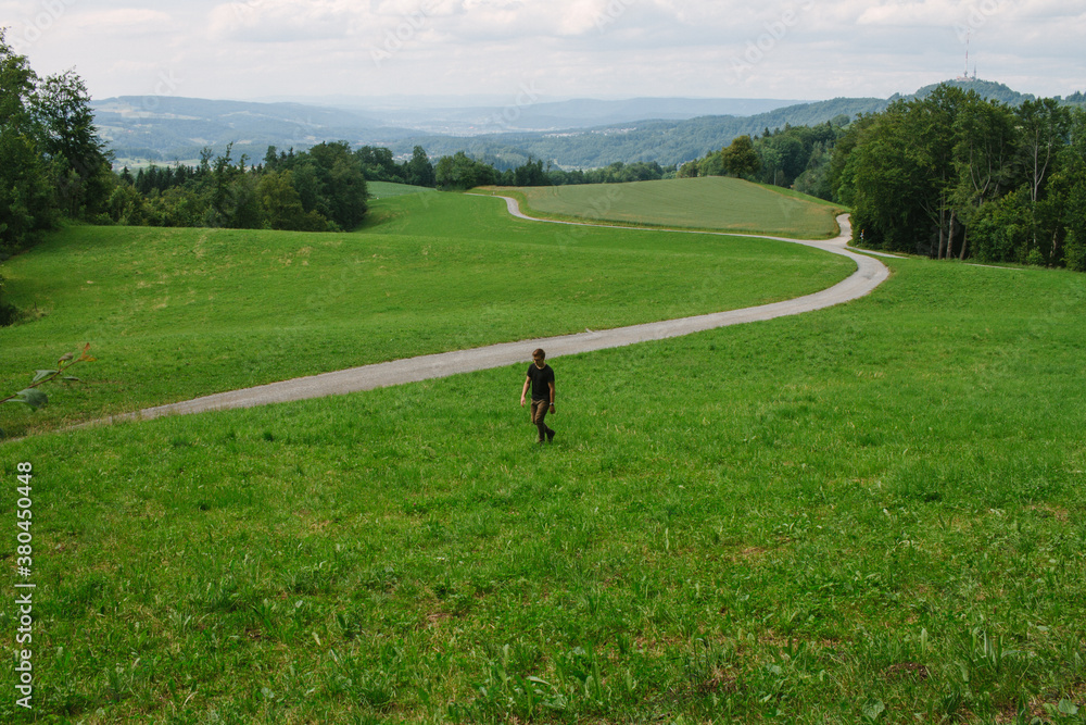 young man walks through field in switzerland young man walks through field in switzerland