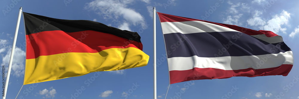 Naklejka premium Waving flags of Germany and Thailand on flagpoles, 3d rendering