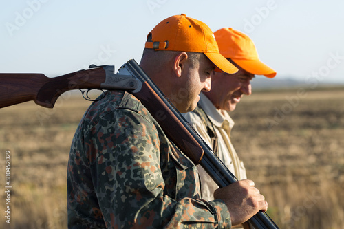 Fototapeta Duck hunters with shotgun walking through a meadow.