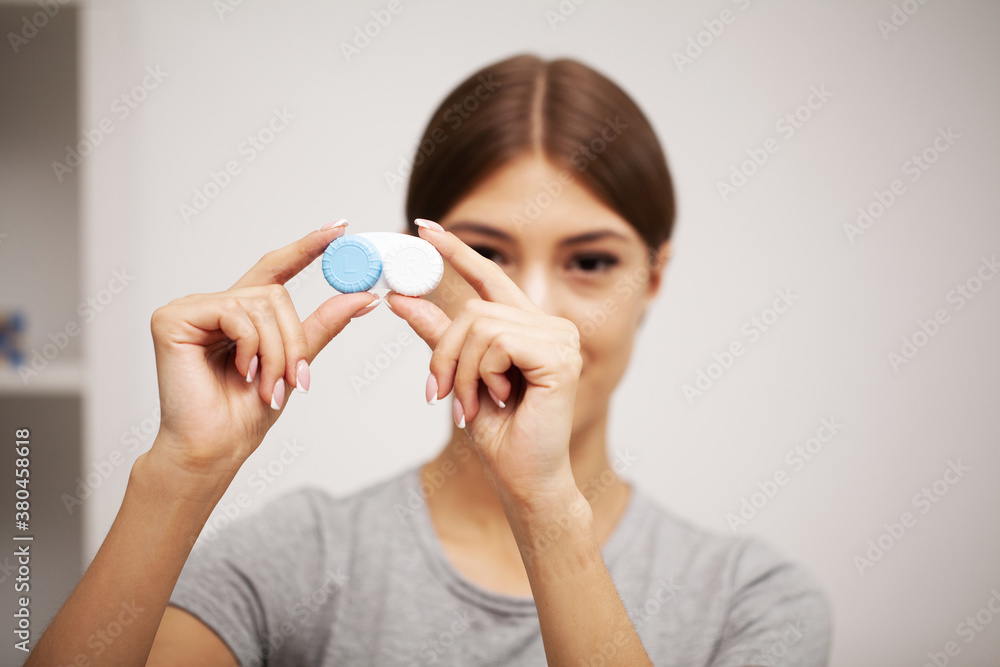 Woman holding plastic container with contact lenses Woman holding plastic container with contact lenses