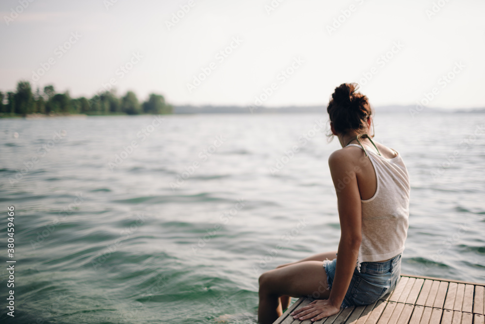 Girl sitting on a pier with her feet in the water