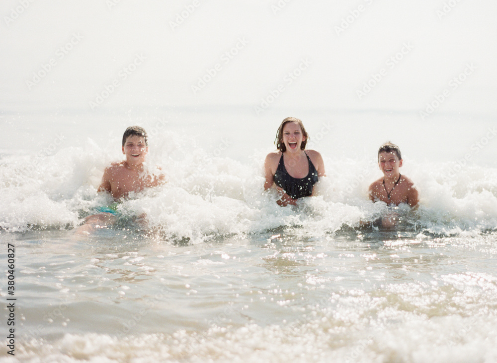 Three kids sitting while waves break on them Three kids sitting while waves break on them