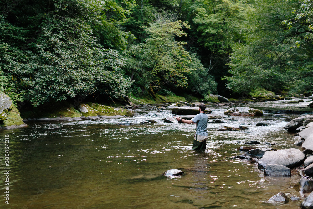 Man fly-fishing in clear river trying to catch fish Man fly-fishing in clear river trying to catch fish