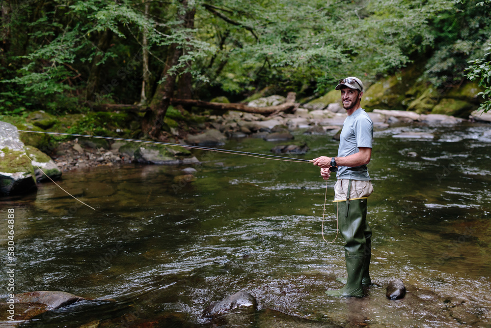 Man fly-fishing in clear river trying to catch fish Man fly-fishing in clear river trying to catch fish