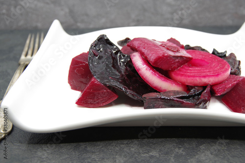 Herring with beets and dried mushrooms on a white plate. Closeup
