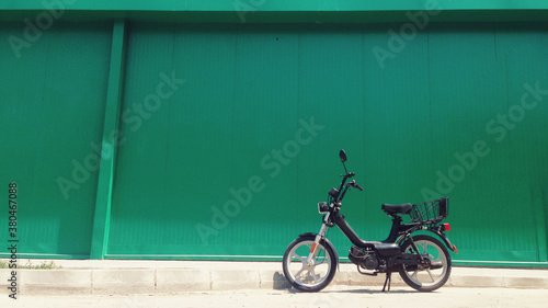 Old black motorcycle infront of green wall photo