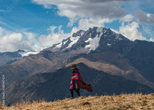 A woman walks across a ridge in the Andes mountains near Cusco, Peru