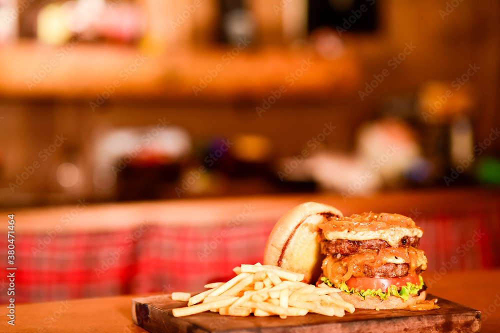 hamburger sandwich with open brioche bread cream cheese fries bacon sauces on the table on blurred background