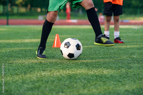 Fototapeta Naklejka Na Ścianę i Meble -  Soccer player kicking ball on field. Soccer players on training session. Close up footballer feet kicking ball on grass.