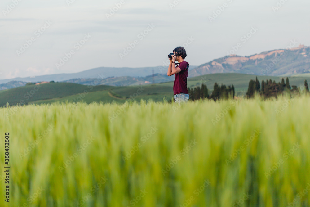 Teenage boy standing in a field in Tuscany with his camera Teenage boy standing in a field in Tuscany with his camera