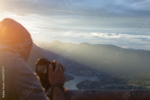 Man filming nature from a viewpoint at sunset photo