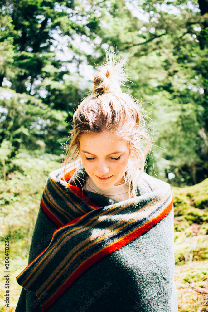 Young Blonde Woman Wrapped In Wool Blanket Standing In Mossy Wooded Area Young Blonde Woman Wrapped In Wool Blanket Standing In Mossy Wooded Area