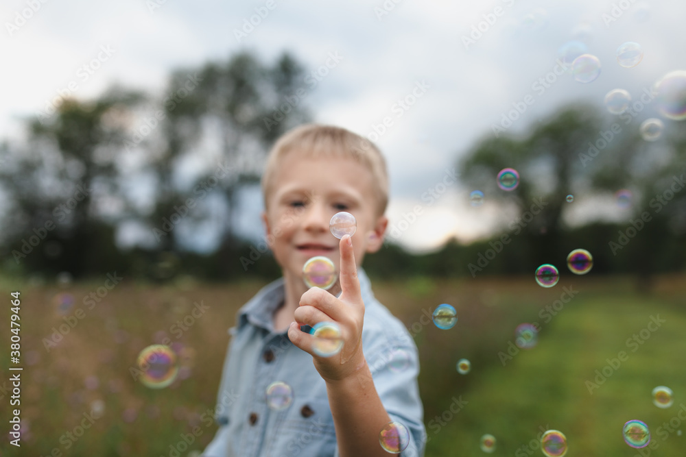 Boy balances a bubble on the end of his finger Boy balances a bubble on the end of his finger