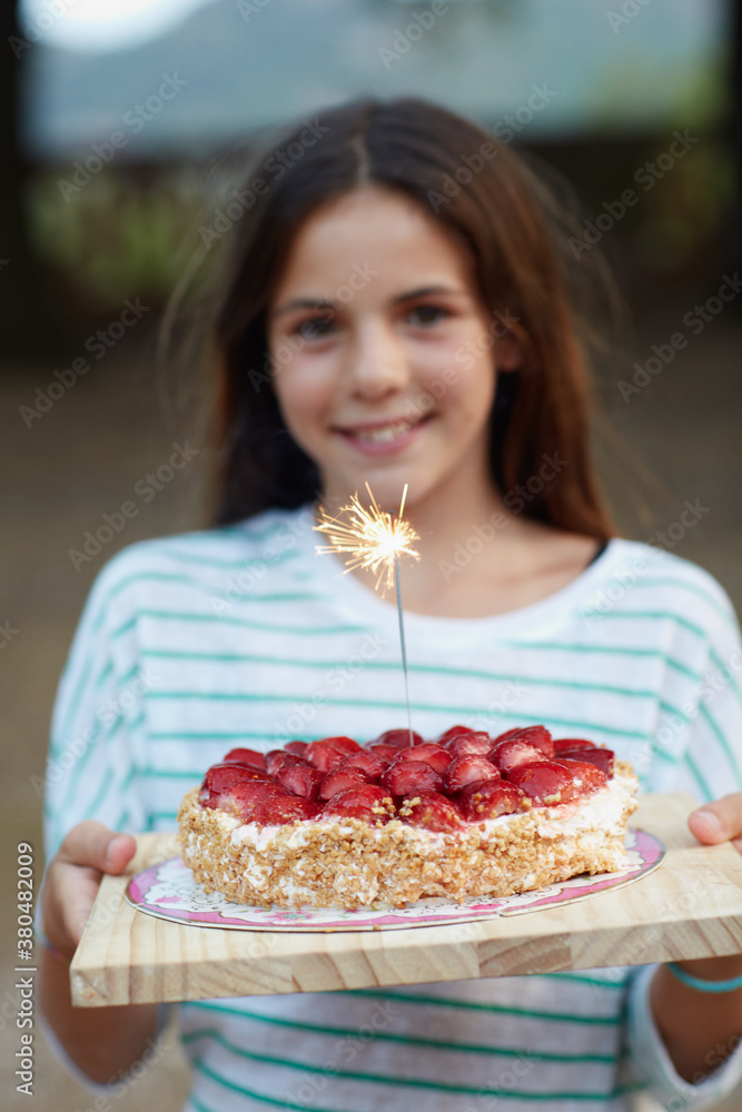 Young beautiful girl holding a birthday cake with sparckles
