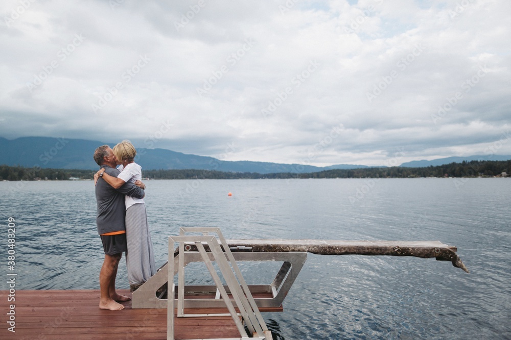 Older couple kissing together outside at lake Older couple kissing together outside at lake