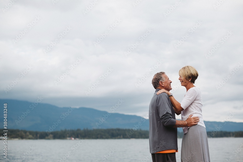 Older couple talking closely together outside at lake Older couple talking closely together outside at lake
