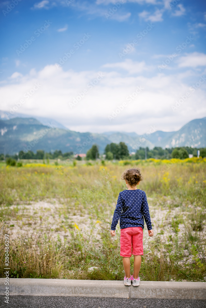 Girl watching the distant mountains. Shot from behind. Girl watching the distant mountains. Shot from behind.