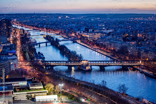 Aerial view of the Seine River and cityscape in Paris France at dusk, with bridges and lights and sunset sky above the horizon © James M. Davidson