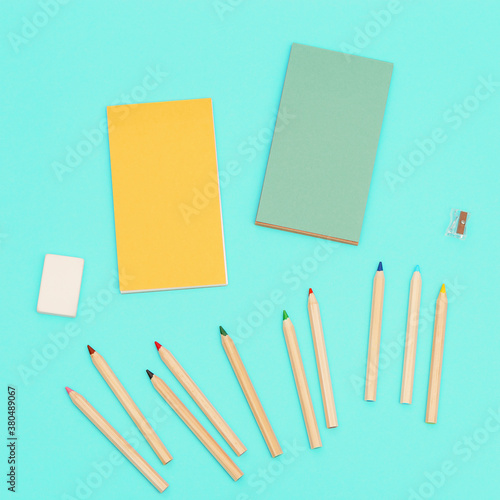 Top view of colored pencils and sketch pad for creativity. Set of wooden multicolored pencils  pencils sharpener  eraser. Design background social media.