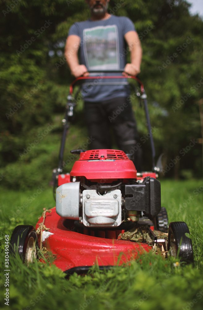 Man with grassmower attacking a wild lawn Man with grassmower attacking a wild lawn