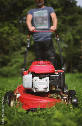Man with grassmower attacking a wild lawn photo