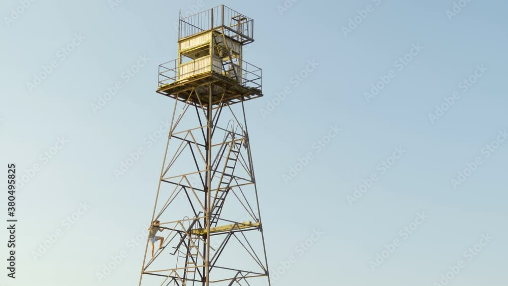 A boy climbing up the metal tower in the cliff A boy climbing up the metal tower in the cliff