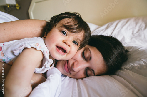 Cute moment of a mother and her daughter smiling and lying on a bed
