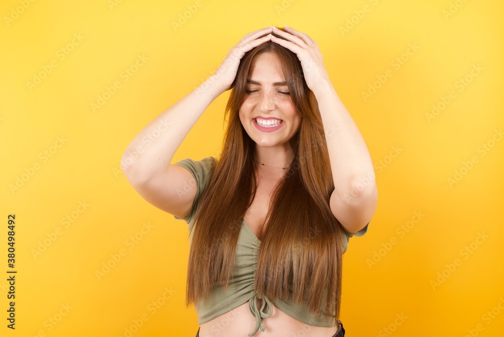 Young woman wearing green shirt suffering from strong headache desperate and stressed because of overwork. Depression and pain concept. Young woman wearing green shirt suffering from strong headache desperate and stressed because of overwork. Depression and pain concept.