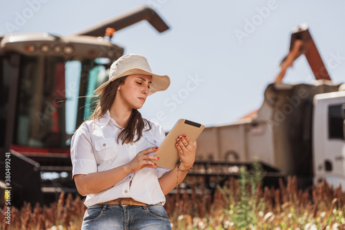 Young woman with tablet on a plantation with harvesting machines photo