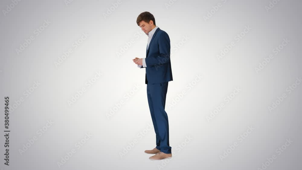 Happy businessman counting money and tucking it inside a jacket pocket on gradient background. Happy businessman counting money and tucking it inside a jacket pocket on gradient background.