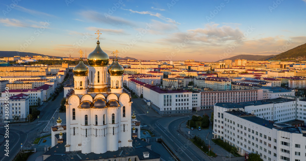 Beautiful morning panorama of the city of Magadan. Aerial view of the cathedral, streets and buildings illuminated by the sun at sunrise. Trinity Cathedral, Magadan, Magadan Region, Far East Russia.