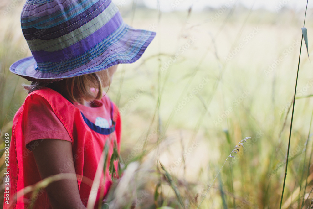 Girl wearing sun hat looking out to grassy field Girl wearing sun hat looking out to grassy field