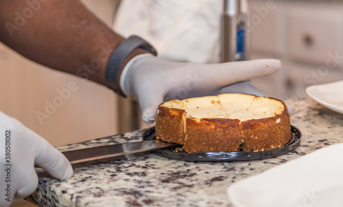 Chef carefully plates cheesecake made from scratch on a granite counter. 