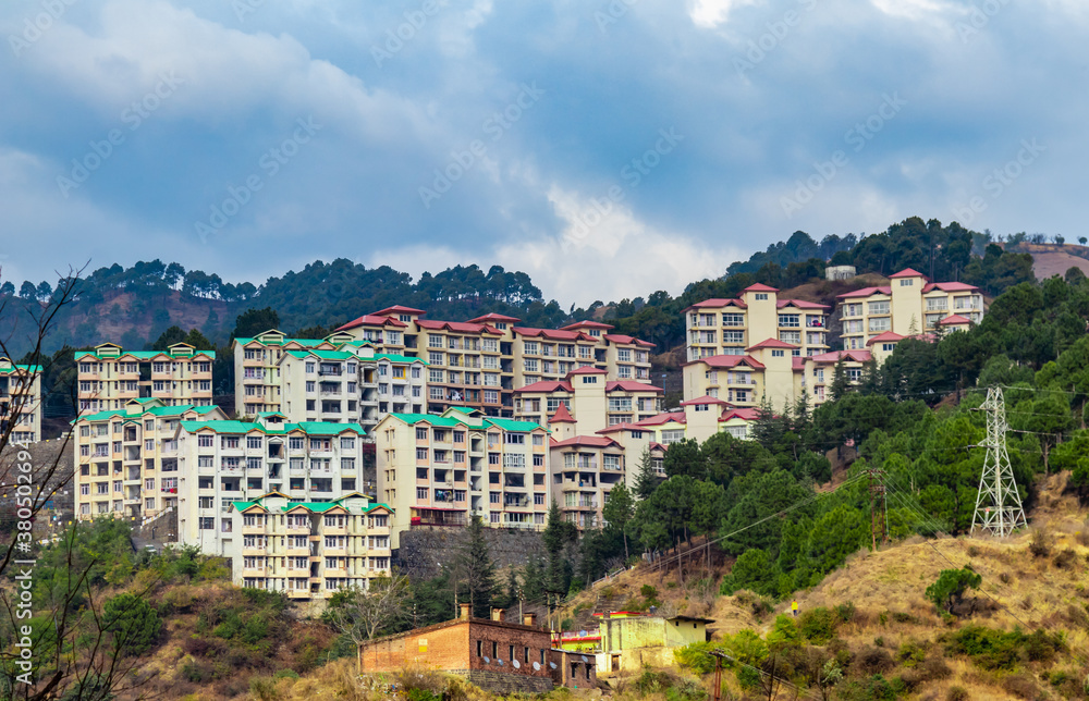 wide shot of buildings along side hills and cloudy blue sky in the background