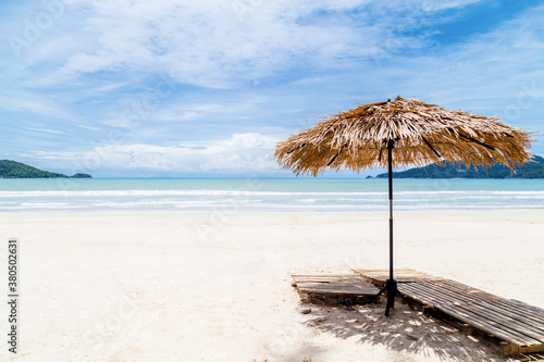 Beach Umbrella made of palm leafs on a perfect white beach in front of Sea.