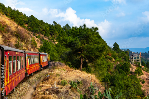 wide shot of train crossing mountain along with trees and cloudy sky in the background
