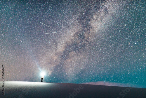 Man Standing on Sand Dune With Flashlight and Milky Way Galaxy in White Sands National Monument NM photo