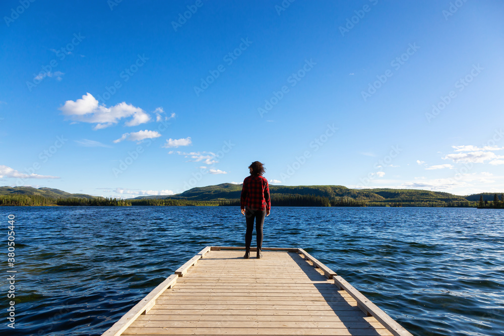 Adventurous Girl on a Wooden Quay at Twin Lakes Campground during a sunny summer day. North of Whitehorse, Yukon, Canada. Concept: travel, adventure, freedom