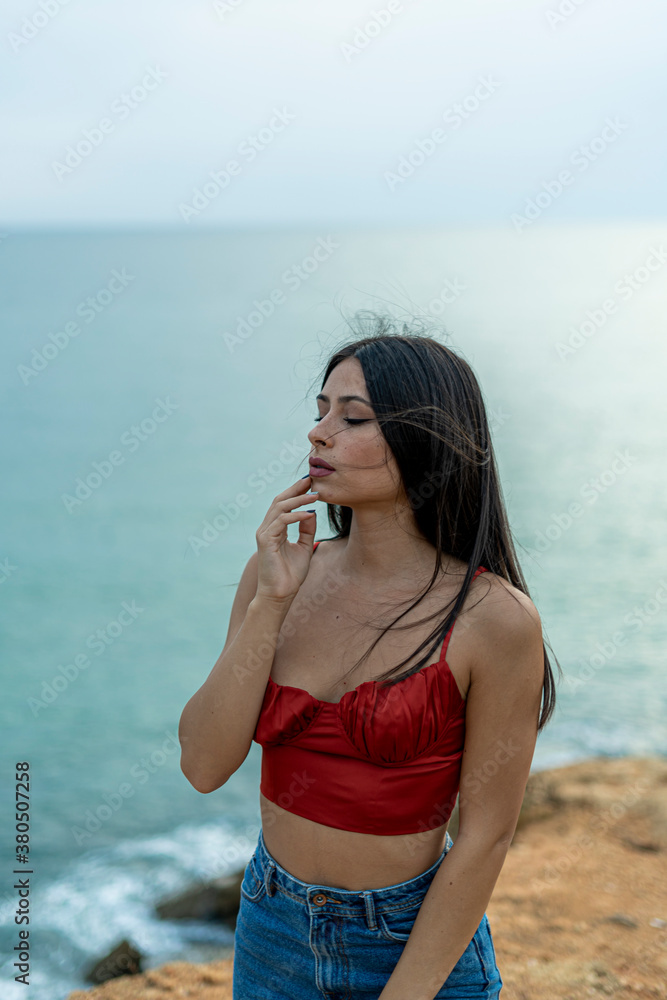 Mujer joven adolescente modelo posando en un acantilado y en la playa. Chica vestida elegante para modelo Mujer joven adolescente modelo posando en un acantilado y en la playa. Chica vestida elegante para modelo
