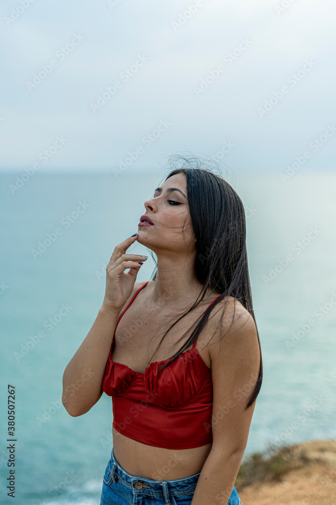 Mujer joven adolescente modelo posando en un acantilado y en la playa. Chica vestida elegante para modelo