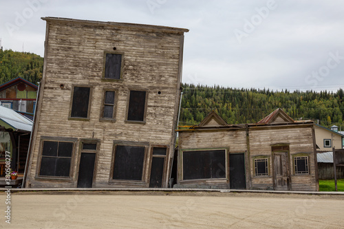 Exterior View of an Old Broken and Slanted House in a small touristic town, Dawson City, during a sunny summer day. Yukon, Canada.