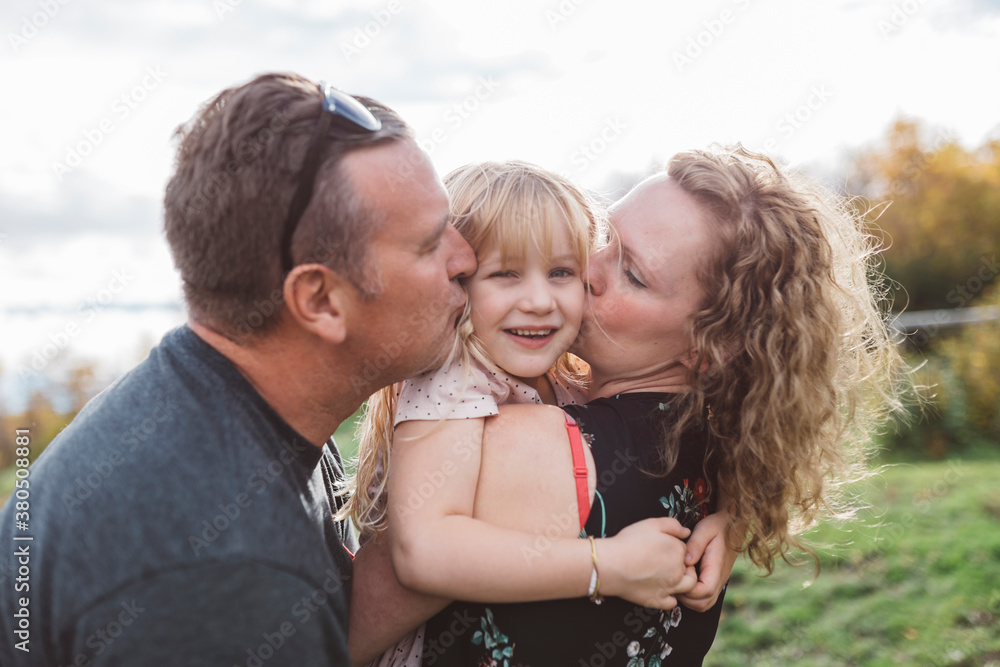 Parents cuddling with their smiling daughter Parents cuddling with their smiling daughter