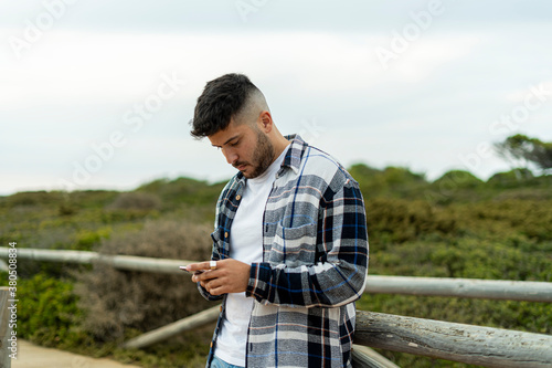 Hombre Joven Adolescente con camisa y camiseta llamando por telefono y cogiendo el movil en el picnik