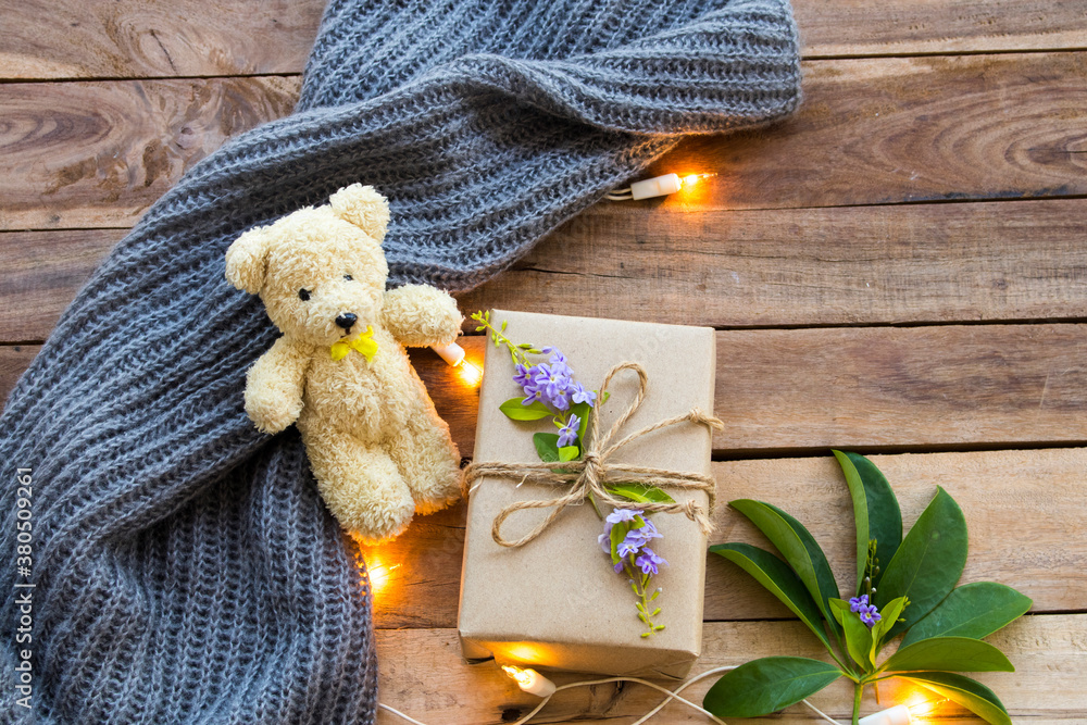 Fototapeta premium gift box for special day in festival day christmas and new year with teddy bear ,knitting wool scarf of lifestyle woman in winter season arrangement flat lay style on background wooden