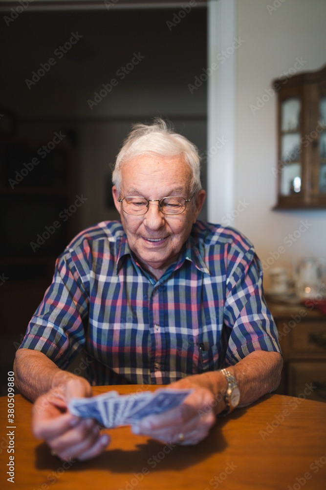 Senior man playing card game at table inside Senior man playing card game at table inside