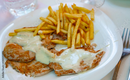 Delicious pork steaks with cream sauce and side dish of crispy fries..