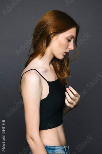 Young redheaded woman looking down against of grey background photo